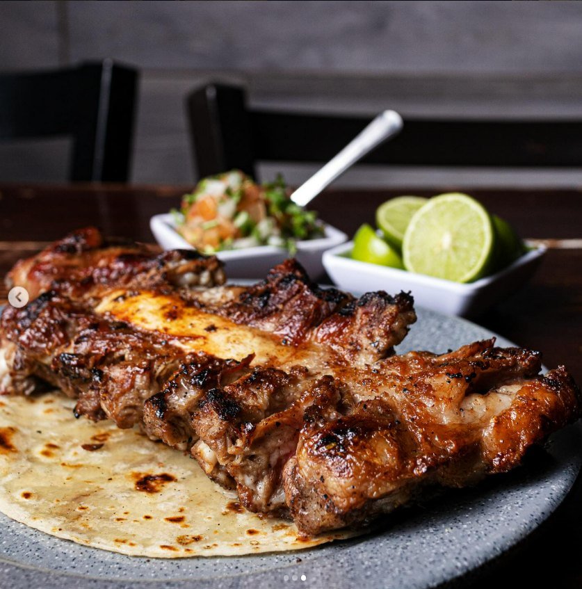 Costilla a la brasa servida sobre tortilla con limón y pico de gallo