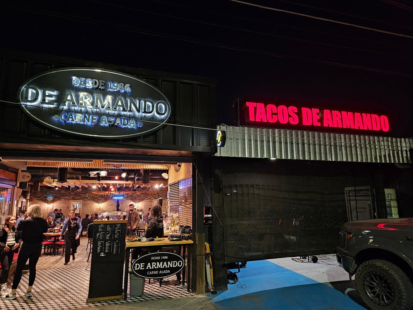 Fachada de Tacos de Armando, sucursal Colosio, iluminada de noche